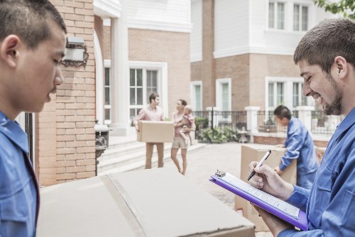 Piano movers handling an upright piano in a Hampton home