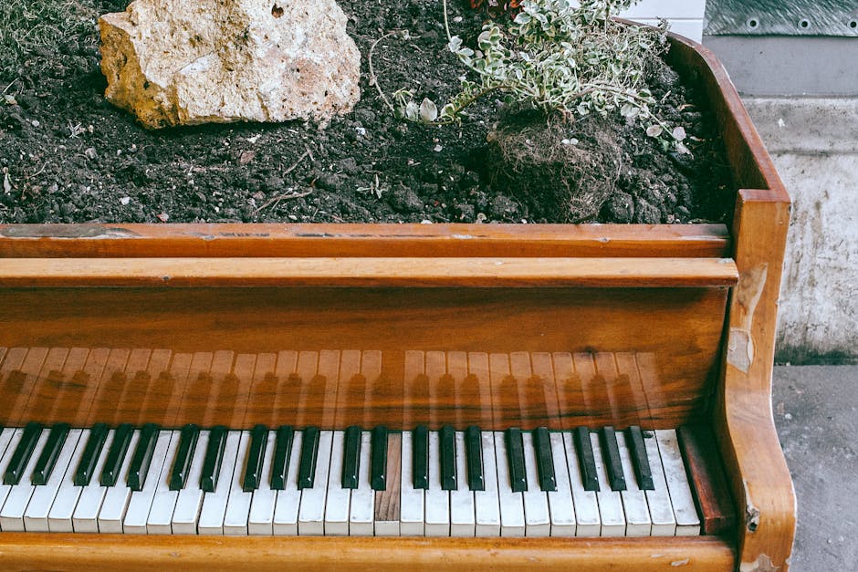 A close-up view of a wooden upright piano during a home relocation process, showing the keyboard with black and white keys and a sheet of music placed on the music stand. The piano is positioned indoo